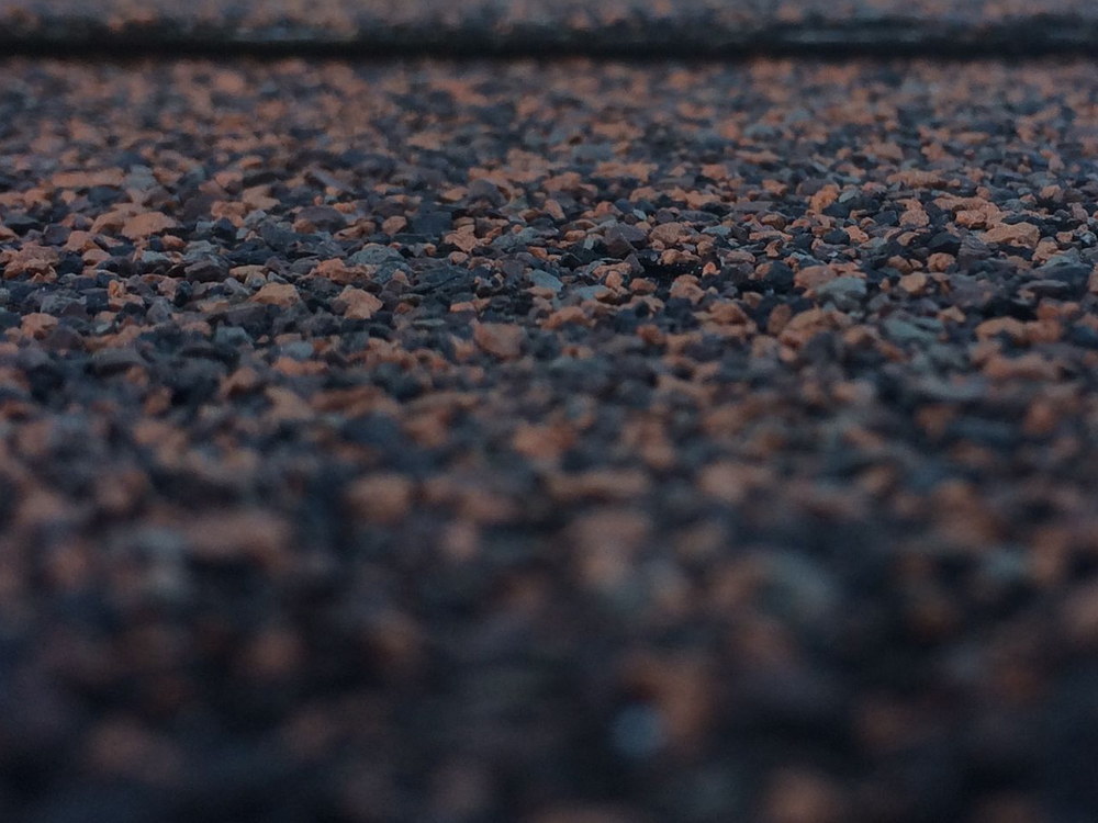 Licensed stock photograph: a close view along a shingle course, the mineral granules in red and charcoal filling the frame.
